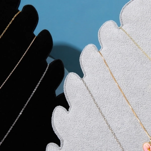 Detail view of gold and silver necklaces on velvet display stands with a pink tulip pendant