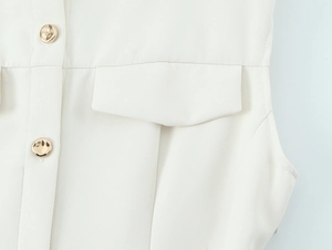 Close-up of ivory crepe dress featuring flap pocket and gold embossed buttons