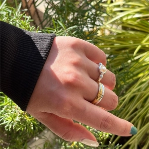 Detail of layered S925 silver pearl ring and two-tone band worn on hand in sunlight