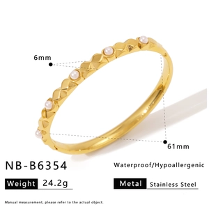 Detail of golden stainless steel bangle with geometric texture and six inlaid pearls
