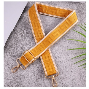 Close-up of mustard yellow ethnic patterned bag strap with golden metal swivel hooks