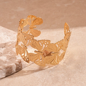 Macro detail of the golden butterfly open bangle with intricate hollow-out metal wings
