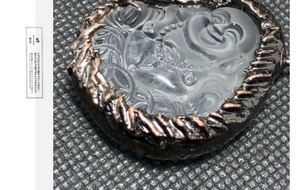 Makroaufnahme von herzförmigem mattiertem Glasanhänger mit Buddha-Relief und Bronzerahmen