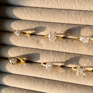 Macro view of gold rings with heart and oval cut cubic zirconia on velvet tray