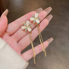 Detail of long floral earrings with cat eye stone, gold fringe, and rhinestone accents