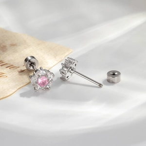 Silver camellia stud earrings with pink and blue gemstones on vintage white background