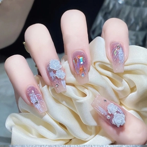 Detail of nude pink nails with purple glitter, 3D white roses and pearls on silk