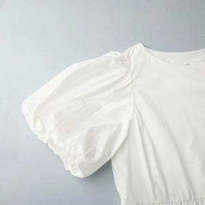 Détail d'une robe en coton blanc montrant des manches bouffantes et col rond