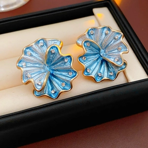 Macro shot of blue enamel flower earrings with gold edges and inlaid rhinestones