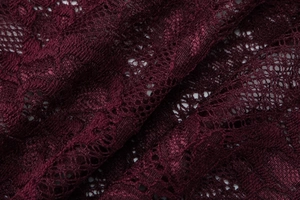 Detailed close-up of intricate burgundy floral lace fabric with sheer mesh texture
