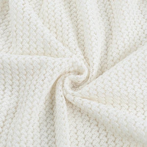 Close-up of white mesh knit fabric texture with elegant hollow lace pattern for summer dress