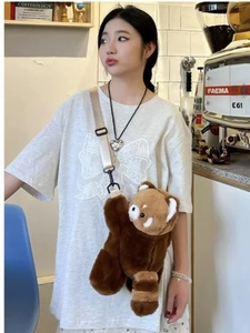 Cute red panda plush crossbody bag with adjustable strap worn by a model in a cafe