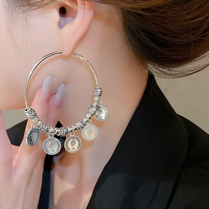 Close-up of vintage geometric silver hoop earrings with Elizabeth II portrait coin pendants