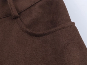 Detail of deep brown suede pants showing precise stitching and soft fabric texture