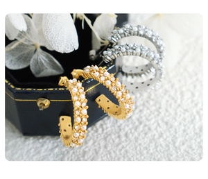 Vue macro de boucles d'oreilles C en or 18 carats et argent avec perles et cristaux