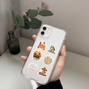 Macro shot of transparent phone case featuring autumn-themed stickers and maple leaf patterns