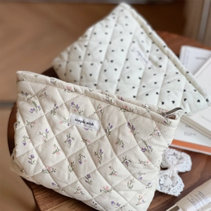 Quilted corduroy floral and heart print makeup bags on a wooden table with lace decor