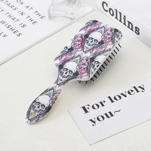 Close-up of skull and pink rose pattern on the back of a cushioned massage hairbrush