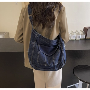 Détail d'un sac bandoulière en denim bleu avec boucle métallique réglable et texture vintage
