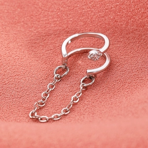 Κοντινό πλάνο από ασημένιο σκουλαρίκι ear cuff με αλυσίδα και ζιργκόν σε ροζ ύφασμα
