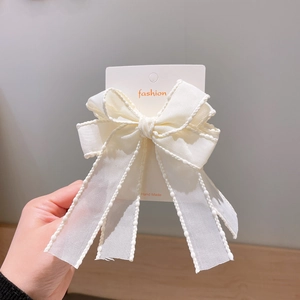 Handmade white bow hair clip for girls with long ribbons on a fashion display card