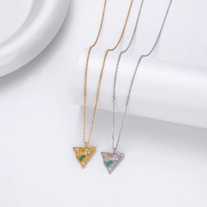 Detail of gold and silver triangle pendants with colorful inlaid gemstones on white stand