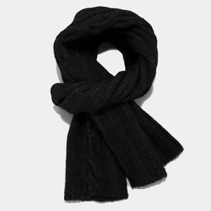 Close-up of black cable knit scarf detail showing thick warm texture and weave pattern