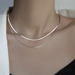 Detail of a minimalist silver double-layer necklace with snake chain and bead chain layers
