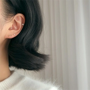 Detail view of 925 silver bow stud and pearl earrings set on a female model's ear
