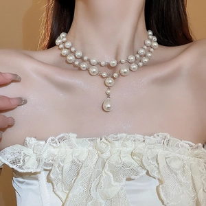 Close-up of double-layered pearl necklace with a teardrop pendant on a model
