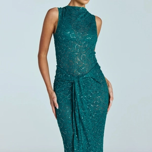 Detailed view of dark green lace dress featuring shimmering sequins and belted waistline