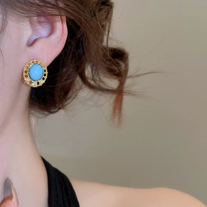 Close-up of vintage gold earrings with oval blue gemstone, small pearls and zircon accents