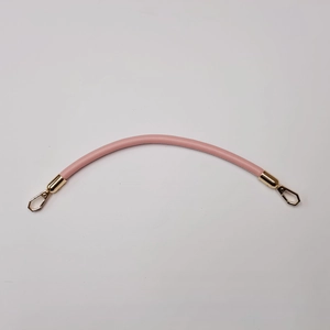 Detailed view of pink leather handbag strap with elegant gold metal snap hooks