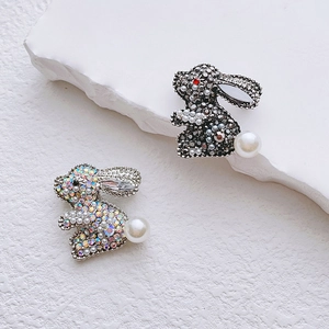 Broches lapin mignonnes avec cristaux brillants et perles sur un socle en pierre blanc