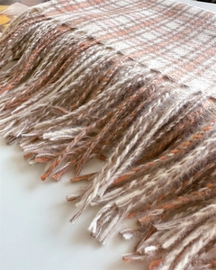 Detailed close-up of soft cashmere-feel plaid scarf with orange and beige tassels