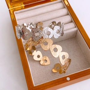 Detailed close-up of gold and silver heart-shaped open bangles with floral engravings