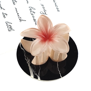 Detailed close-up of a pink gradient flower hair claw clip on marble background