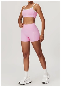 Detail of pink yoga set showing high-waist shorts and sports bra with white contrast trim
