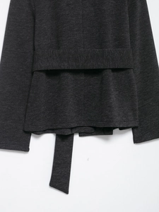 Close-up of soft dark grey knitted fabric texture with matching tie belt detail