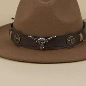 Detail of a brown felt fedora with leather band featuring a silver longhorn cattle emblem