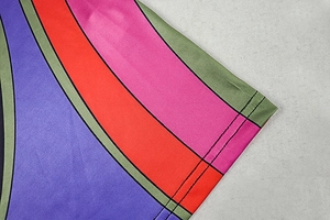 Close-up of vibrant geometric knit fabric with detailed stitching on multi-color dress