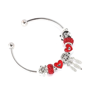 Macro detail of silver beaded bracelet with red heart charms and a cat dangle pendant