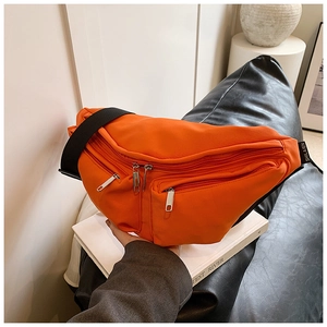Detail view of bright orange crossbody chest bag with adjustable wide black shoulder strap