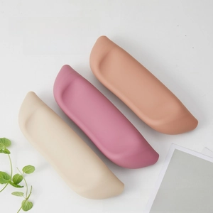 Three rolled-up silicone baby bibs in soft earth tones for portable storage and travel