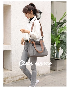 Detail of grey canvas tote bag with brown leather straps and vertical zipper accent