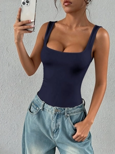 Close-up of a women's dark blue square neck sleeveless crop top paired with denim jeans