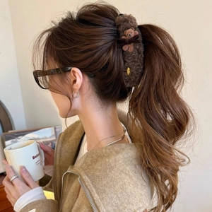 Detail of dark brown plush hair claw with teddy bear and velvet bow on model