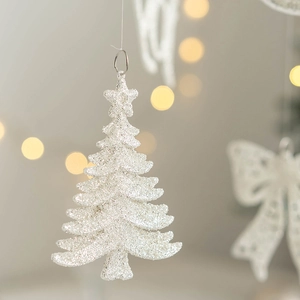 Glittery white Christmas tree hanging ornament with silver ring and warm bokeh background