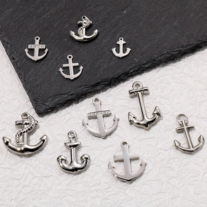Detailed view of silver anchor pendants with rhinestones on black slate and white paper