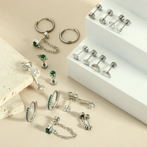 Detail of silver piercing set featuring emerald green zircons on stone display